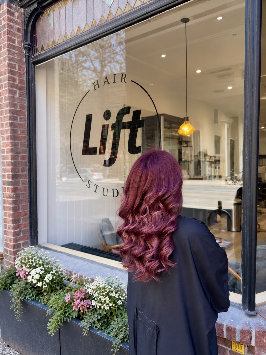 Glossy magenta waves outside Lift Hair Studio beside flower-filled planters